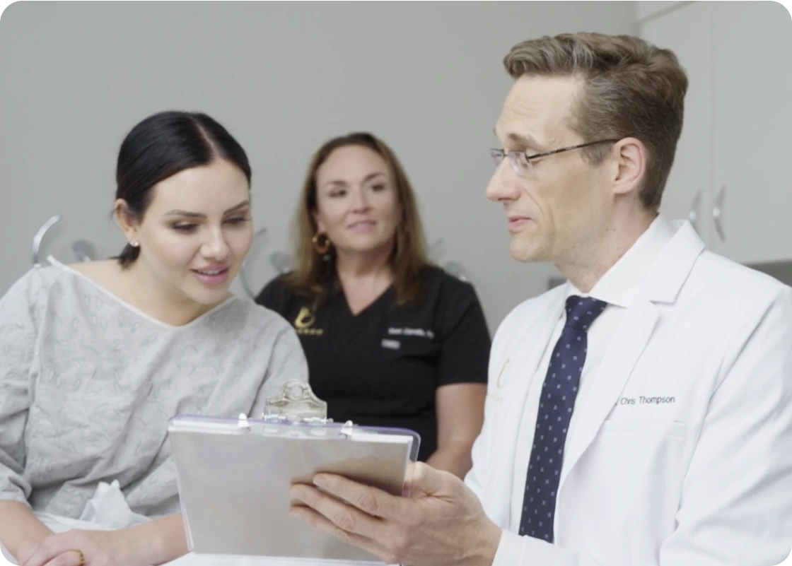 A doctor consulting a patient on the day of procedure with a nurse in the background